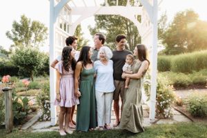 Family members gather for outdoor portraits in a lush garden setting at sunset.
