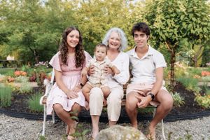 Family members sit together on garden steps during an outdoor photo session.