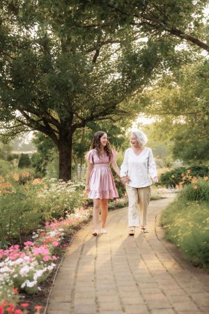 People stroll along a flower-lined garden path during a summer evening.
