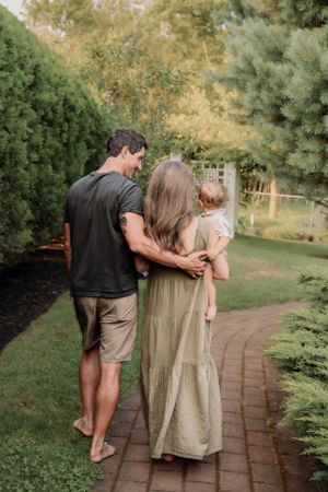 Family walking together on a brick path through a lush garden landscape.