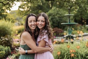 Friends sharing embraces and laughter in a blooming garden during sunset.