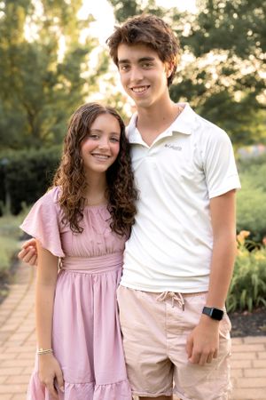 Two people in coordinating outfits posing together in a sunny garden setting.