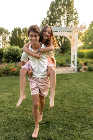 Playful piggyback ride moment captured in a lush green garden.