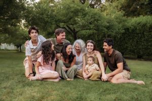Extended family lying together on grass for outdoor portrait session.
