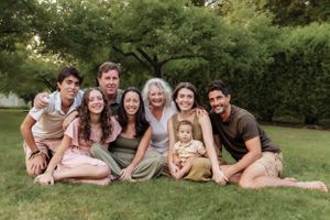 Large family group lounging on grass for casual outdoor photo.