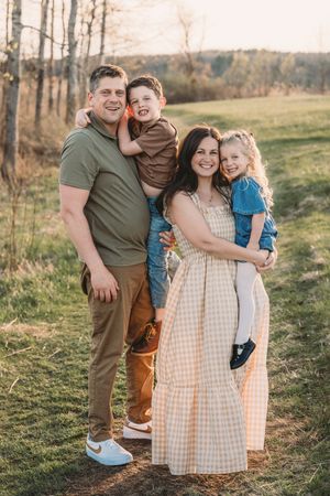 Family portrait session in golden sunlight with rustic outdoor setting.