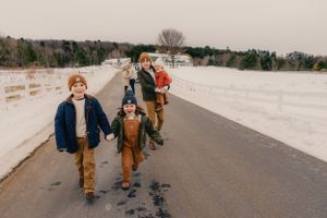Family walking together on a snowy path in winter clothing.