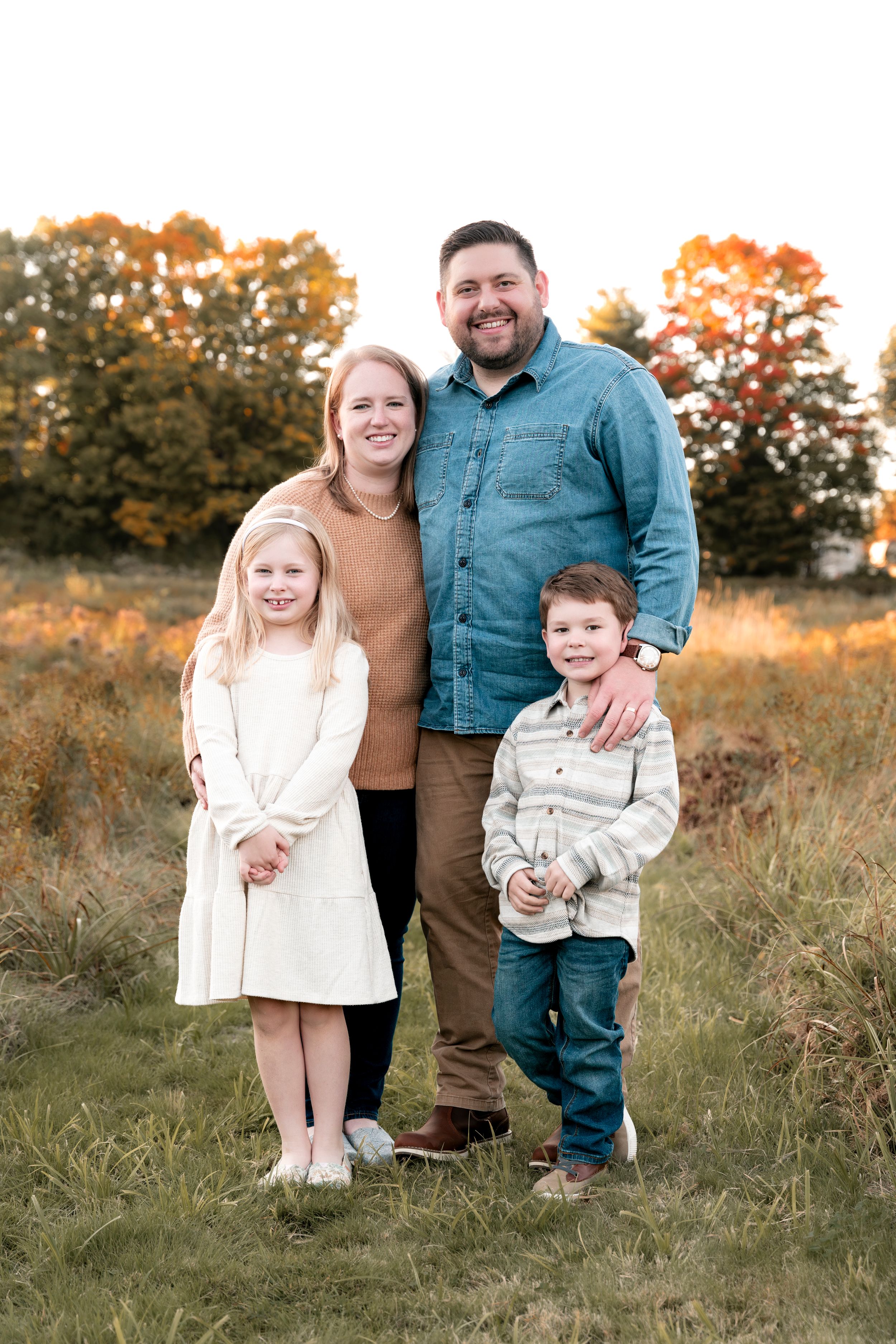 Family portrait in a golden autumn field with tall grass.