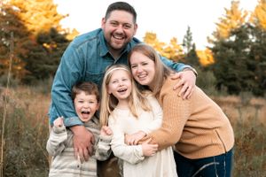 Joyful family embracing and laughing together in an autumn field.
