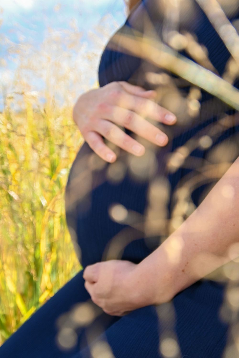 Close-up of hands playing a flute or recorder instrument against a blurred yellow and natural background.