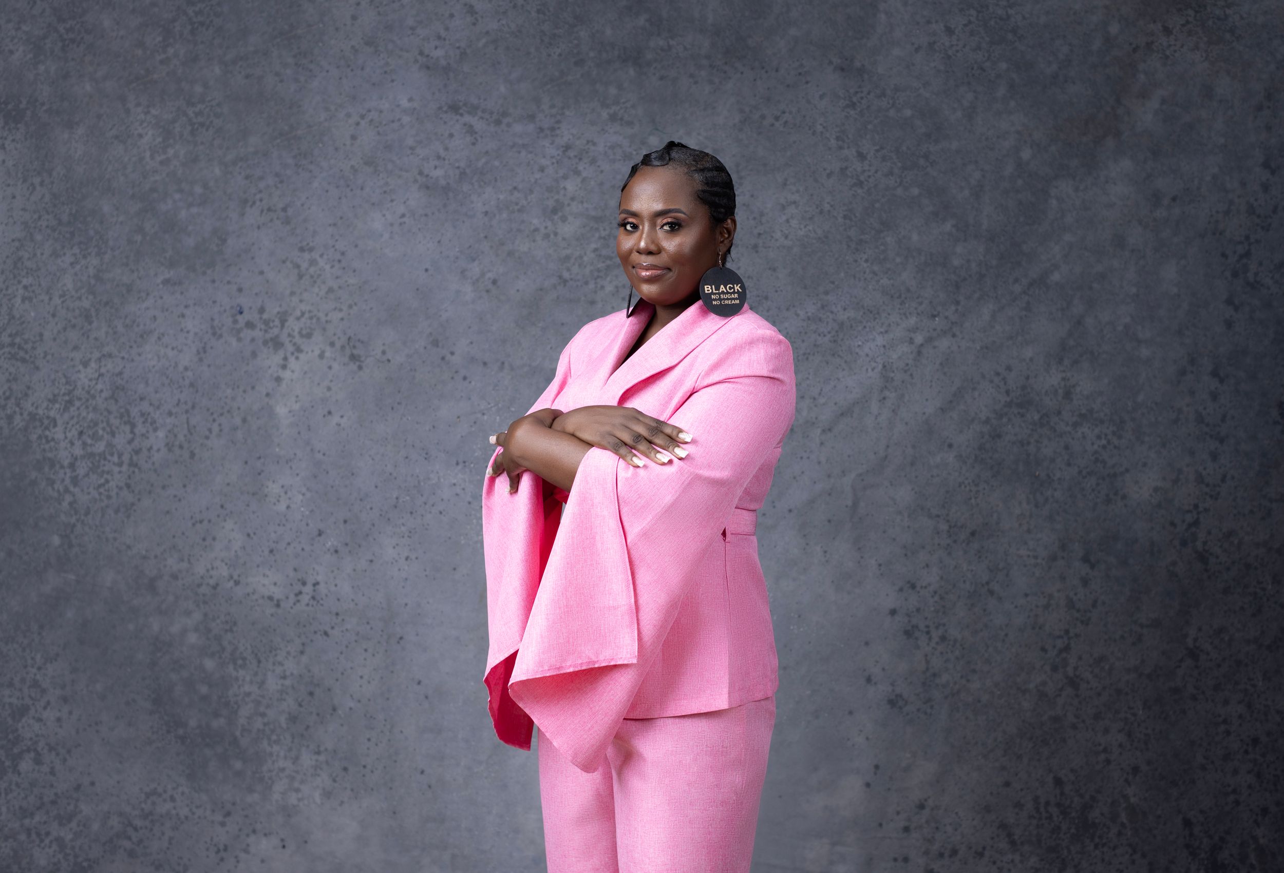 Confident pose in vibrant pink suit against textured studio backdrop.