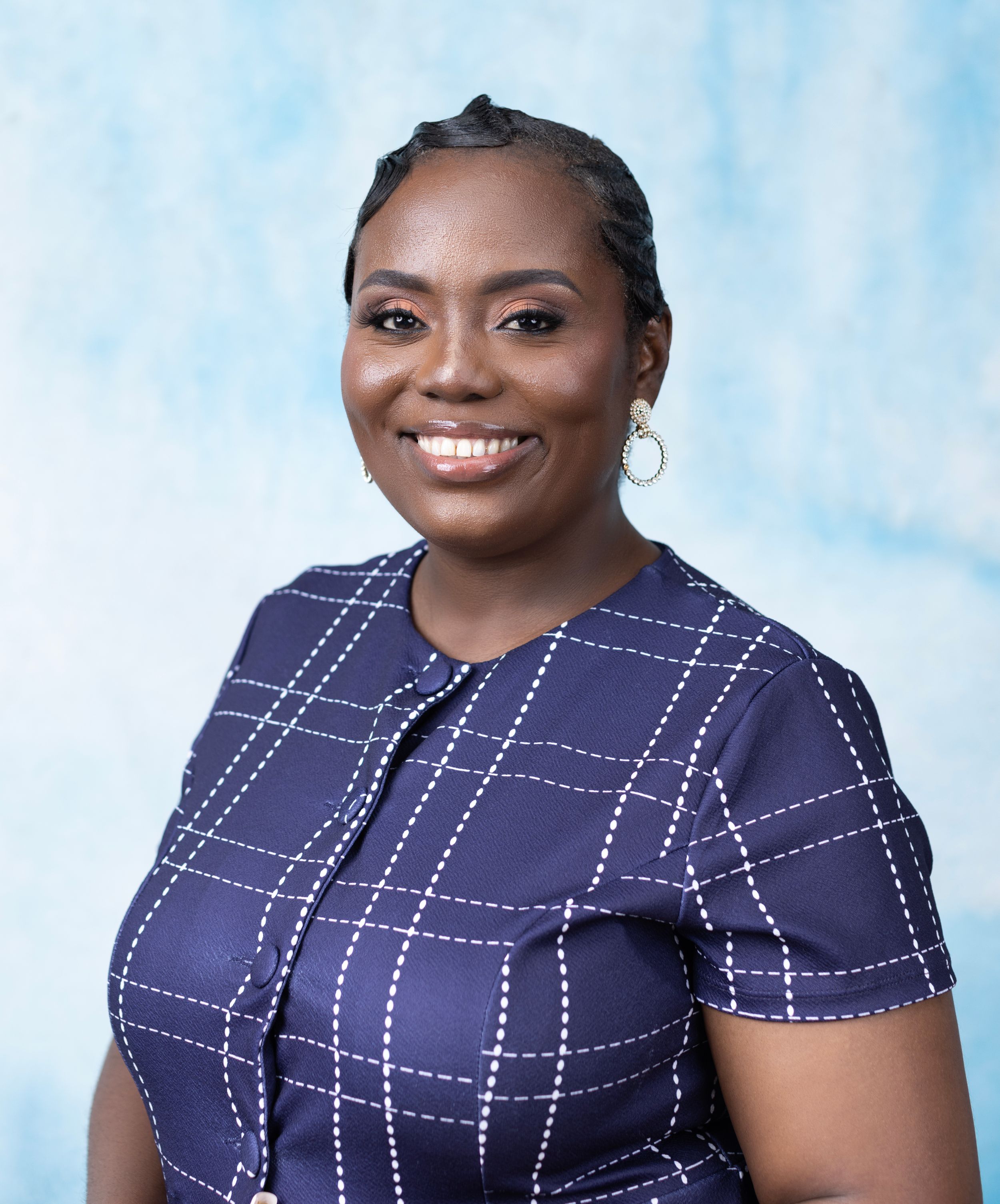 Professional portrait of someone wearing a navy blue windowpane pattern dress against a light blue background.