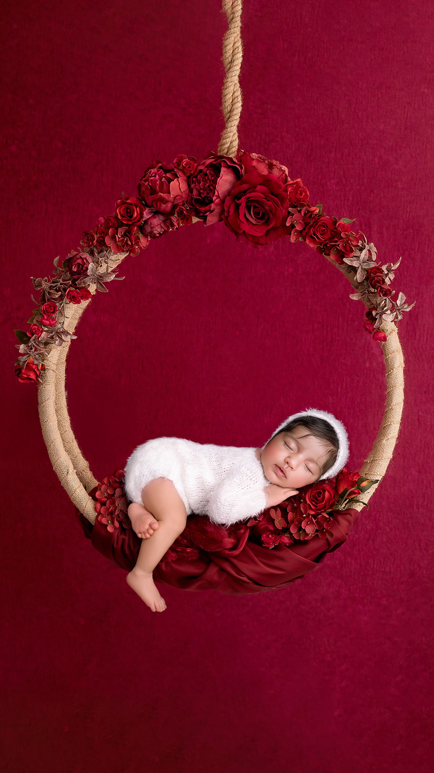 Newborn baby girl on a swing posed safely in West London studio