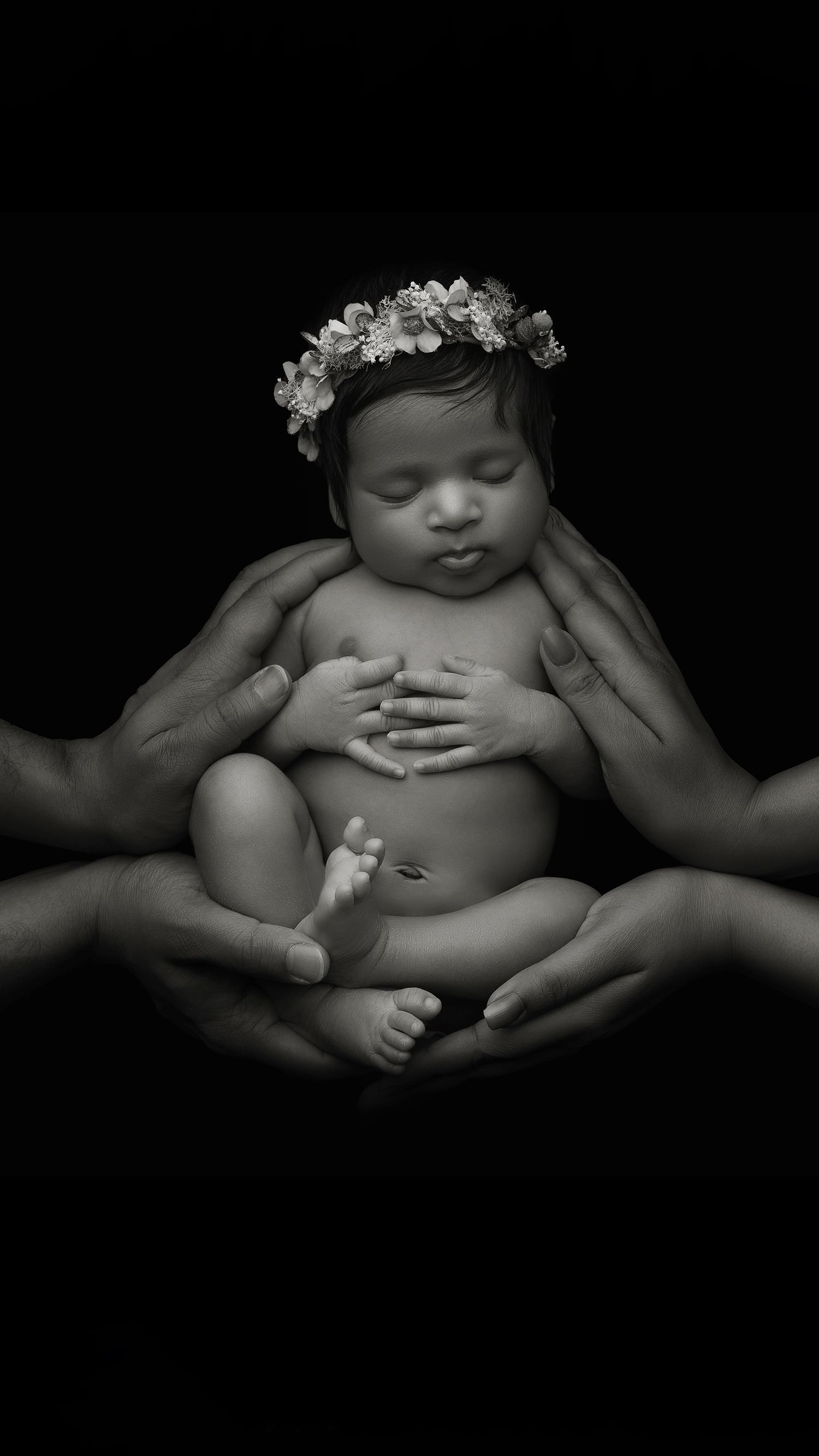 Newborn black and white family portrait with parents holding baby with their hands