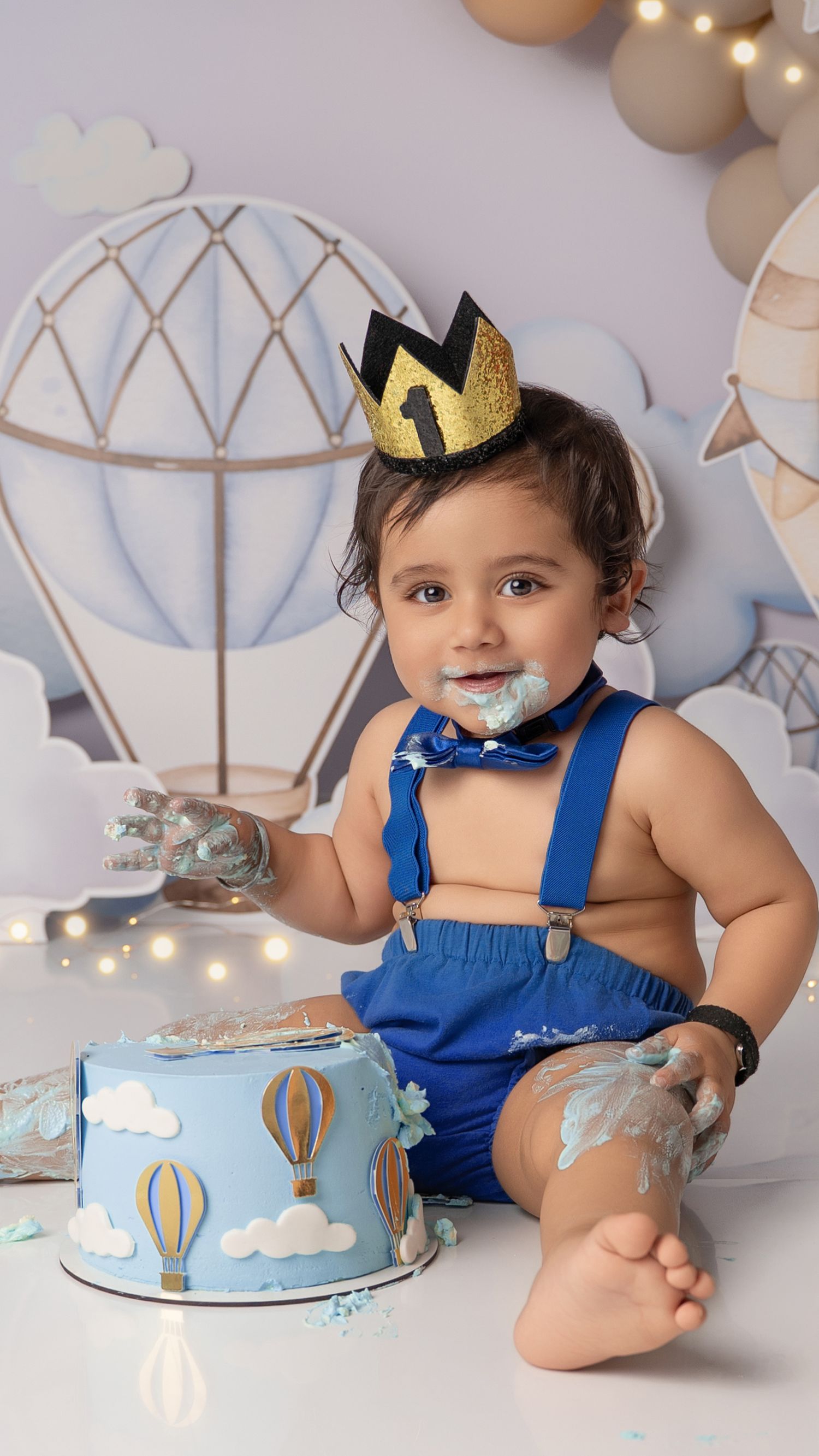 Smiling one-year-old baby boy enjoying cake smash session in Hayes studio