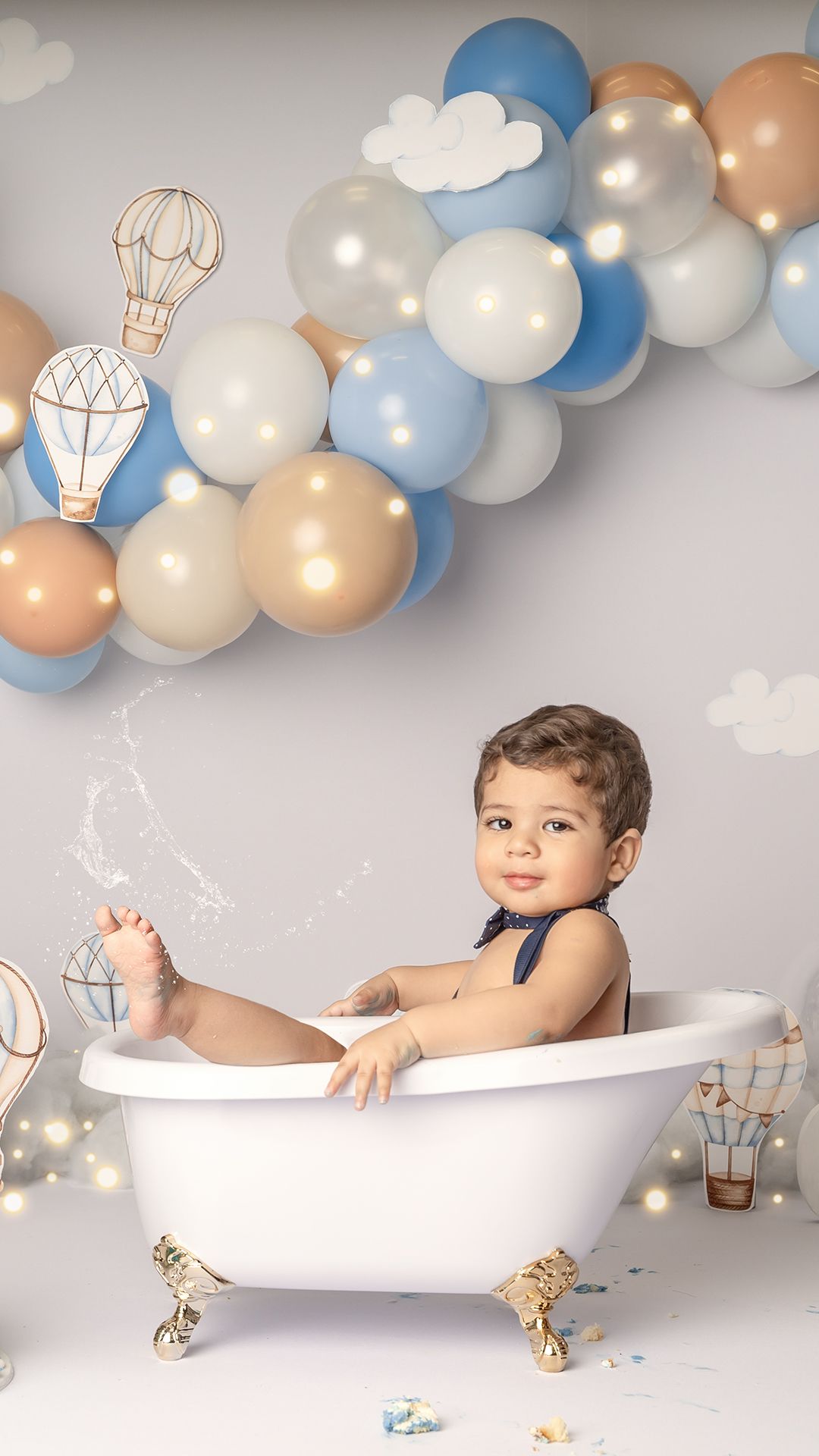 Smiling one-year-old baby enjoying splash bath session after cake smash photoshoot in Hayes, West London studio