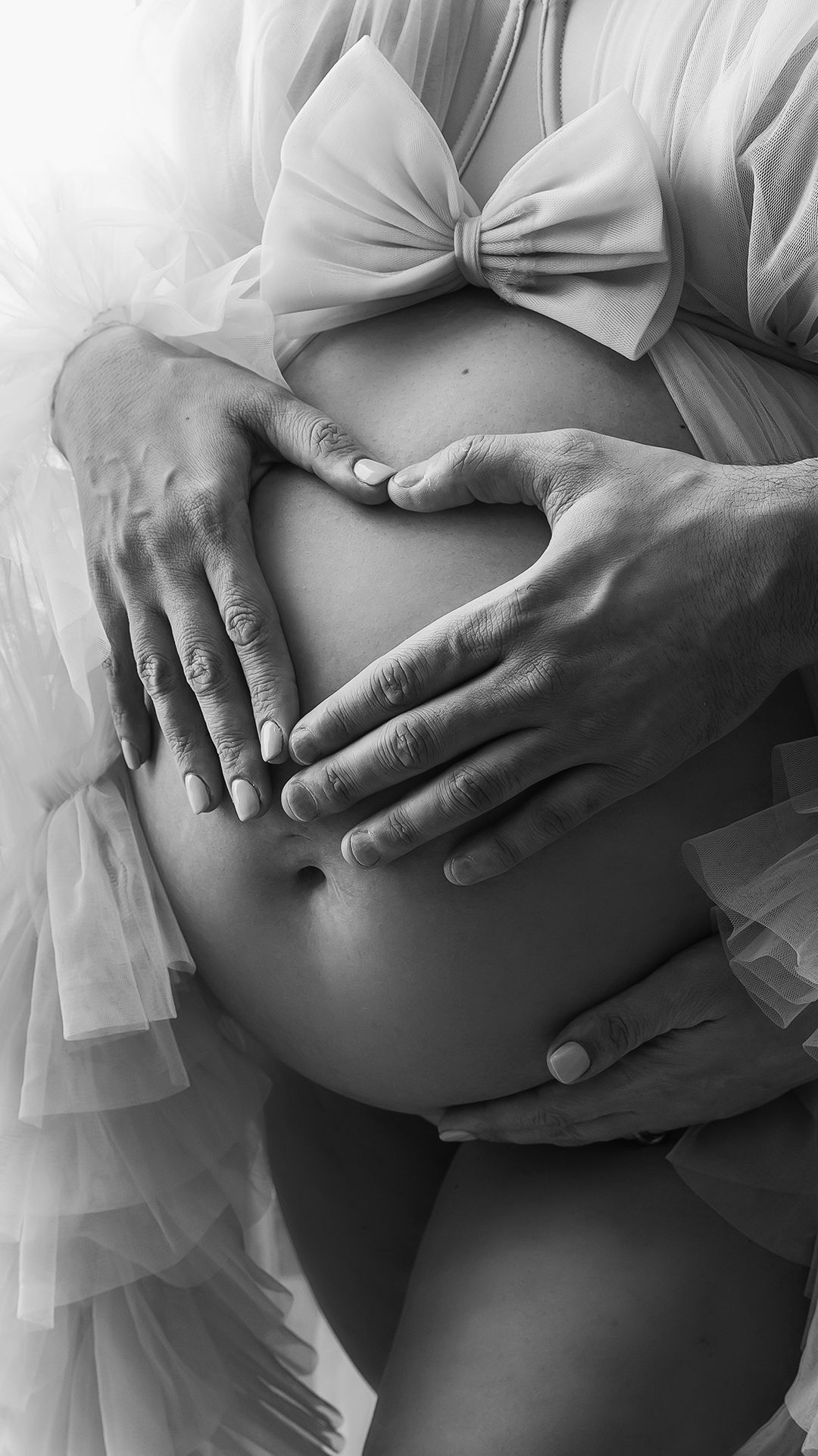 Artistic maternity portrait of pregnant woman and her husband holding baby bump at 32 weeks in London