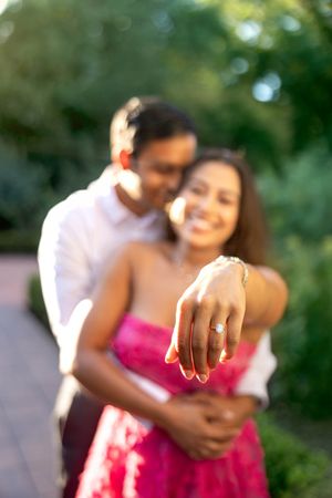 Engaged couple show off Engagement Ring in garden at sunset
