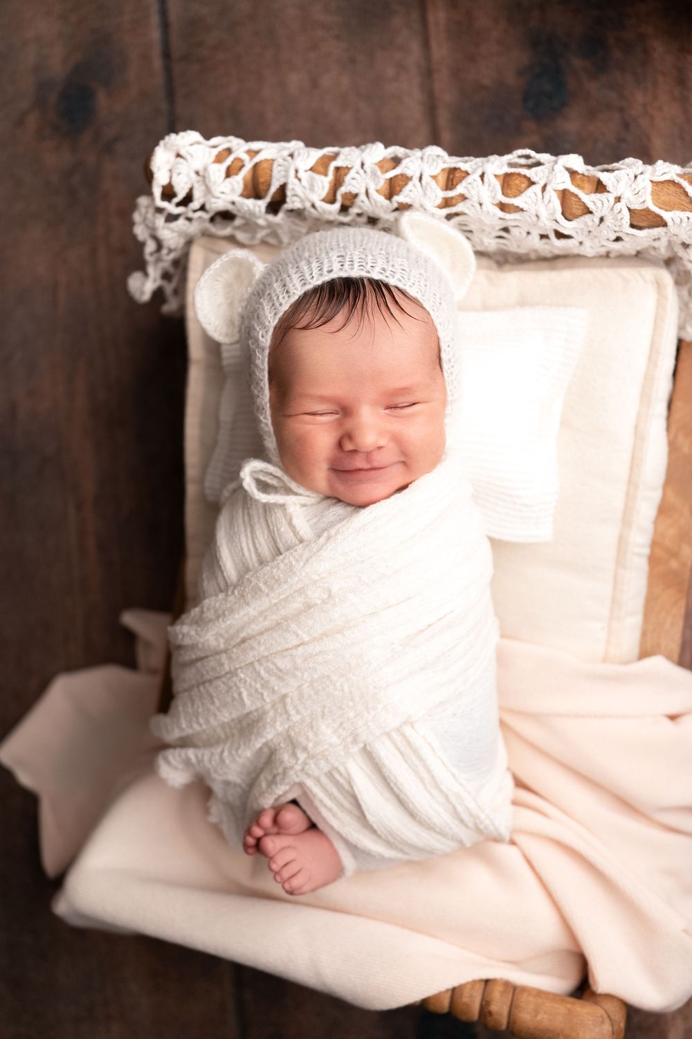 A sleeping baby wrapped in white linen blankets rests peacefully in a series of connected portrait photographs.