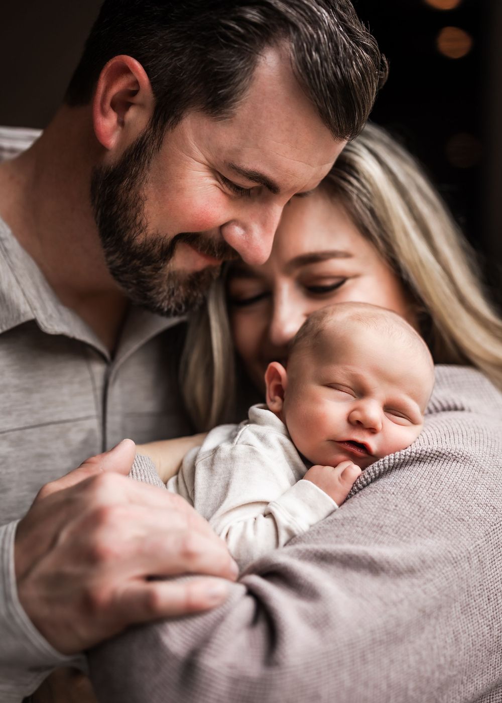 A couple tenderly holds their sleeping newborn baby, sharing a loving family portrait moment.