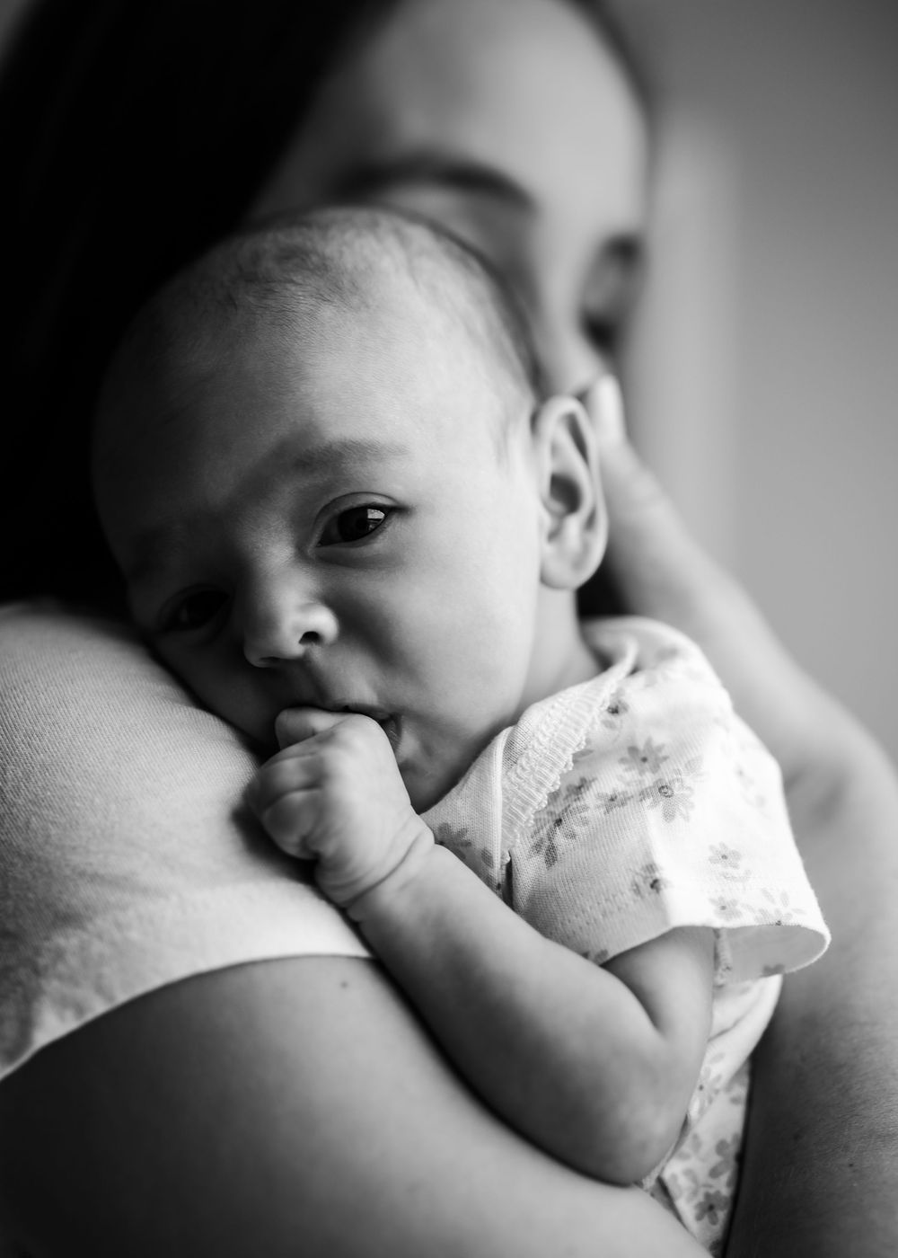 Black and white series showing tender moments of breastfeeding between mother and infant in natural lighting.