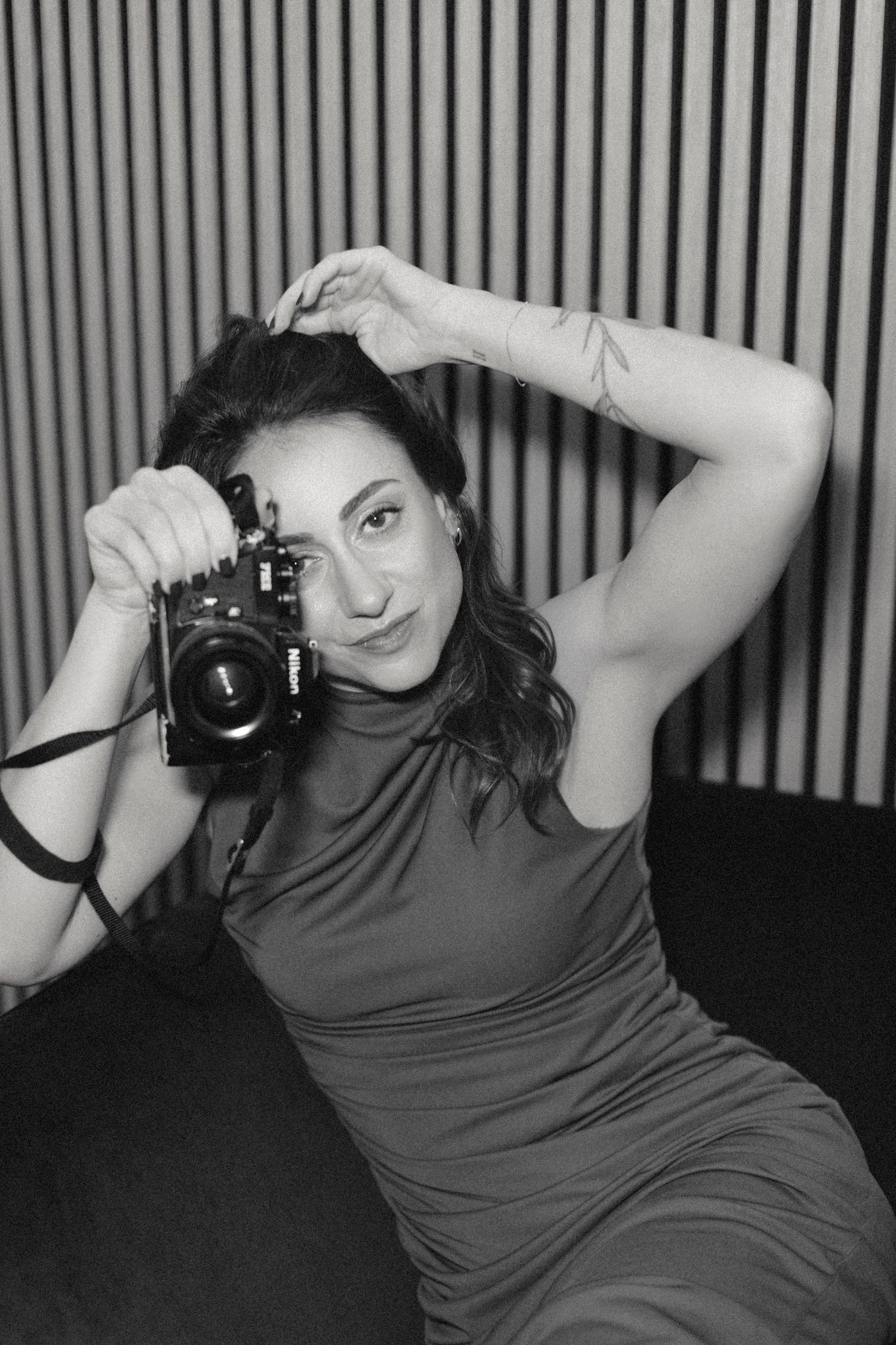 Alice Santella, destination wedding photographer based in Rome, Italy, photographed with her camera in a relaxed black and white portrait