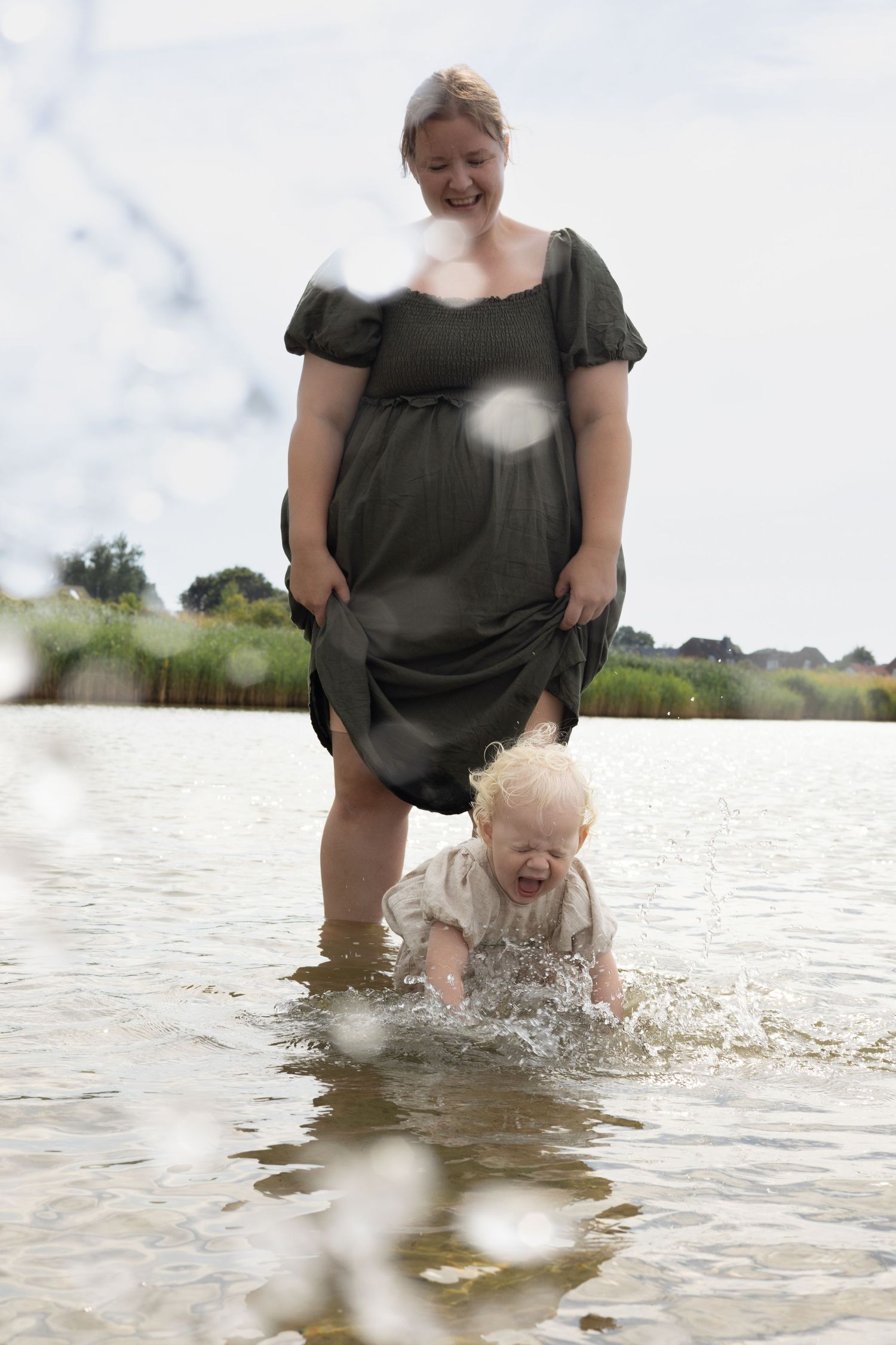 Mother and small child playing in shallow water on a summer day at the shore.