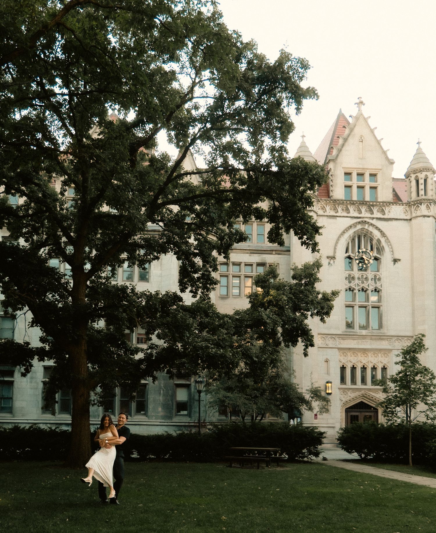 Wedding couple dancing on the lawn in front of a Gothic revival building.