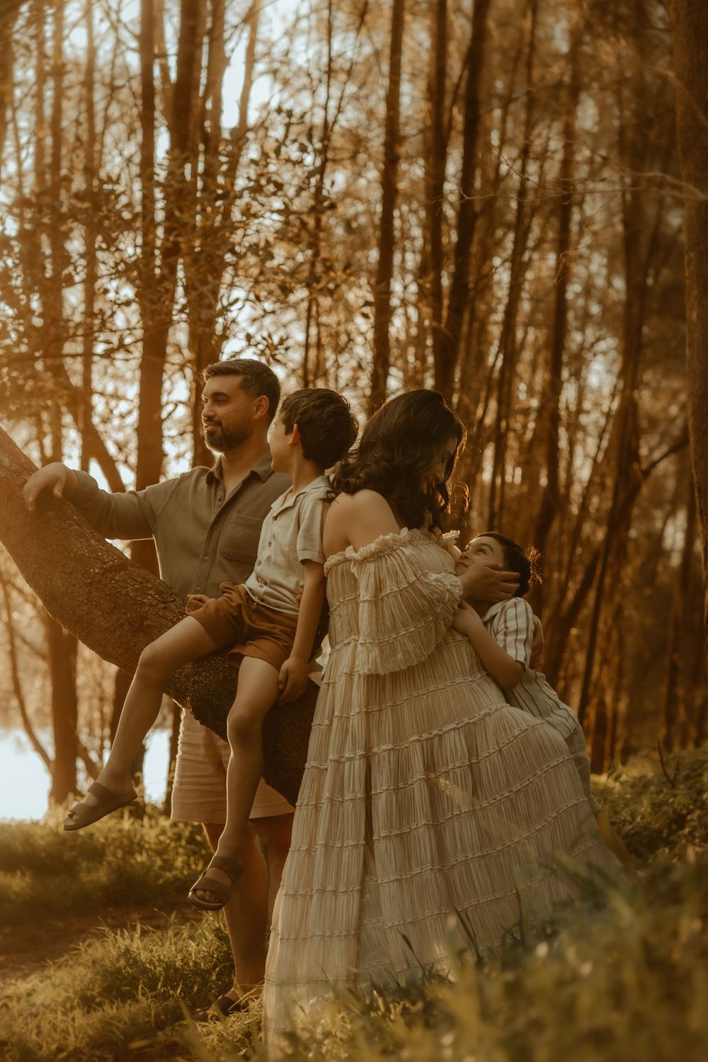 A dreamy sepia-toned forest scene shows people in vintage-style clothing standing together in warm sunlight.