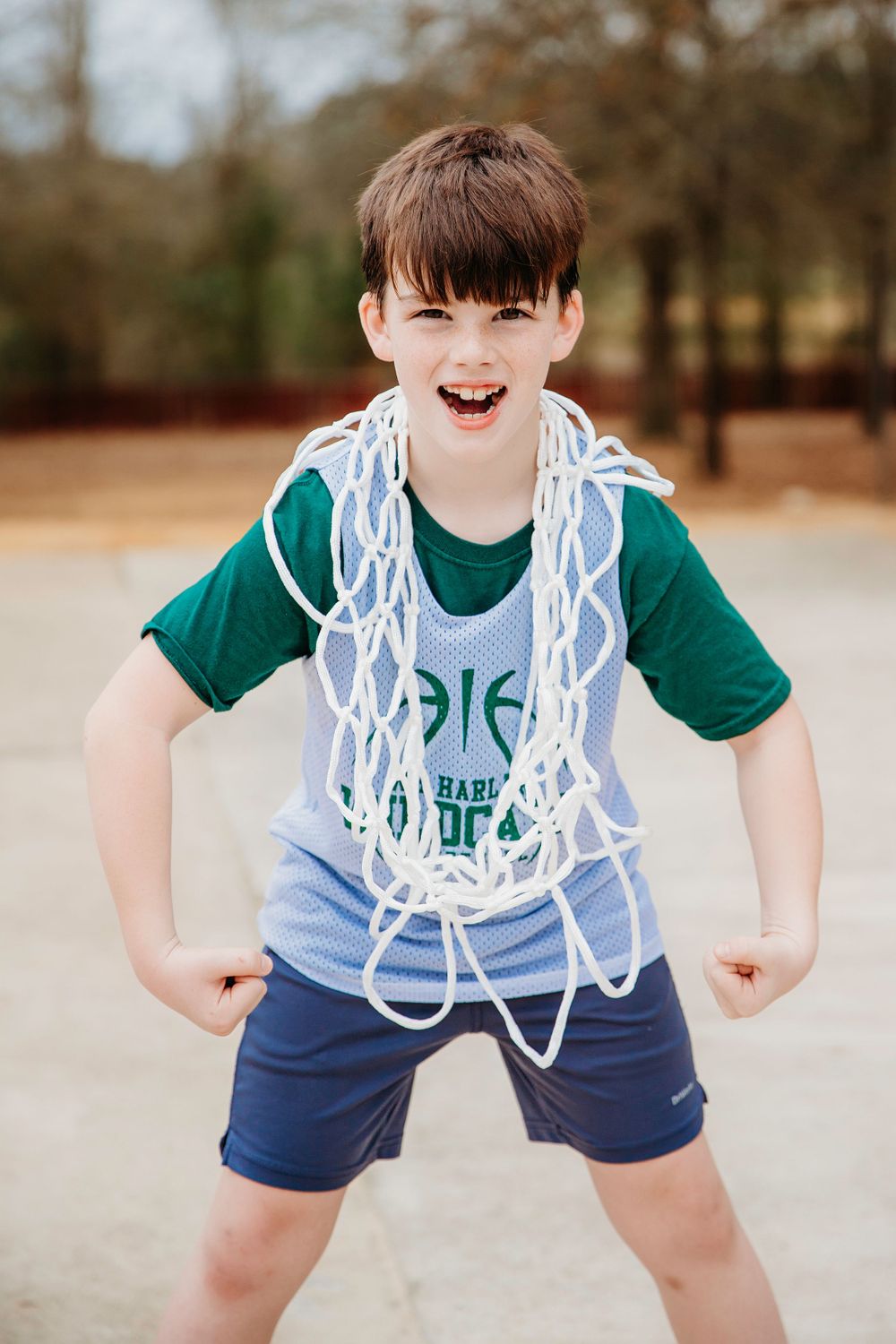 Basketball player poses playfully with white net draped around shoulders.