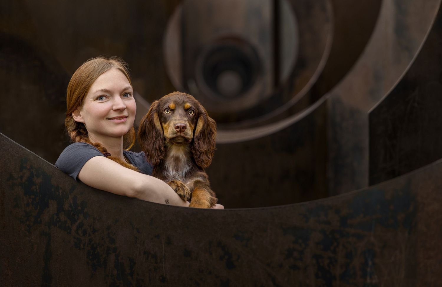 A heartwarming moment with a working cocker puppy being held inside a large rustic metal structure.