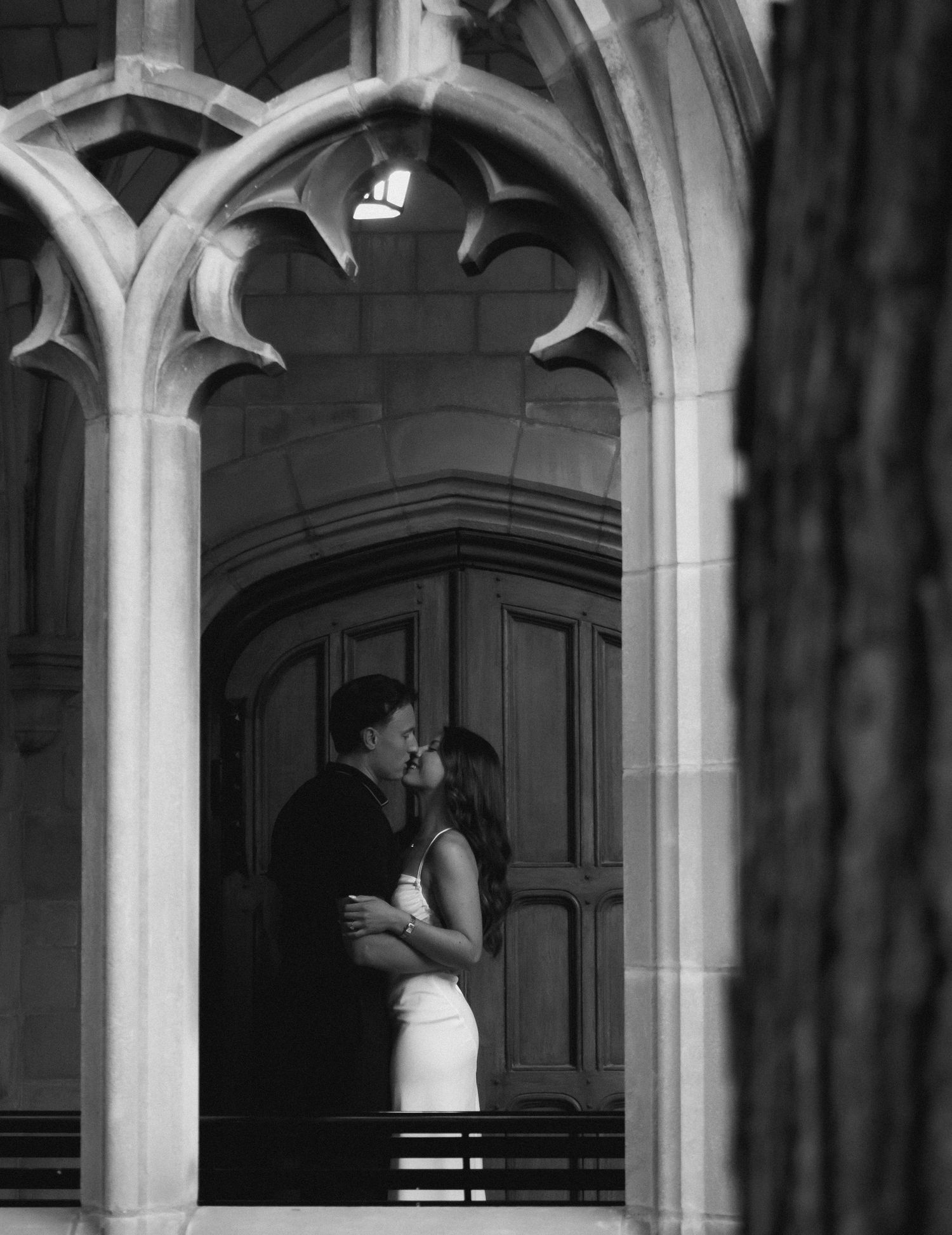 A tender moment shared beneath ornate Gothic architecture in black and white.