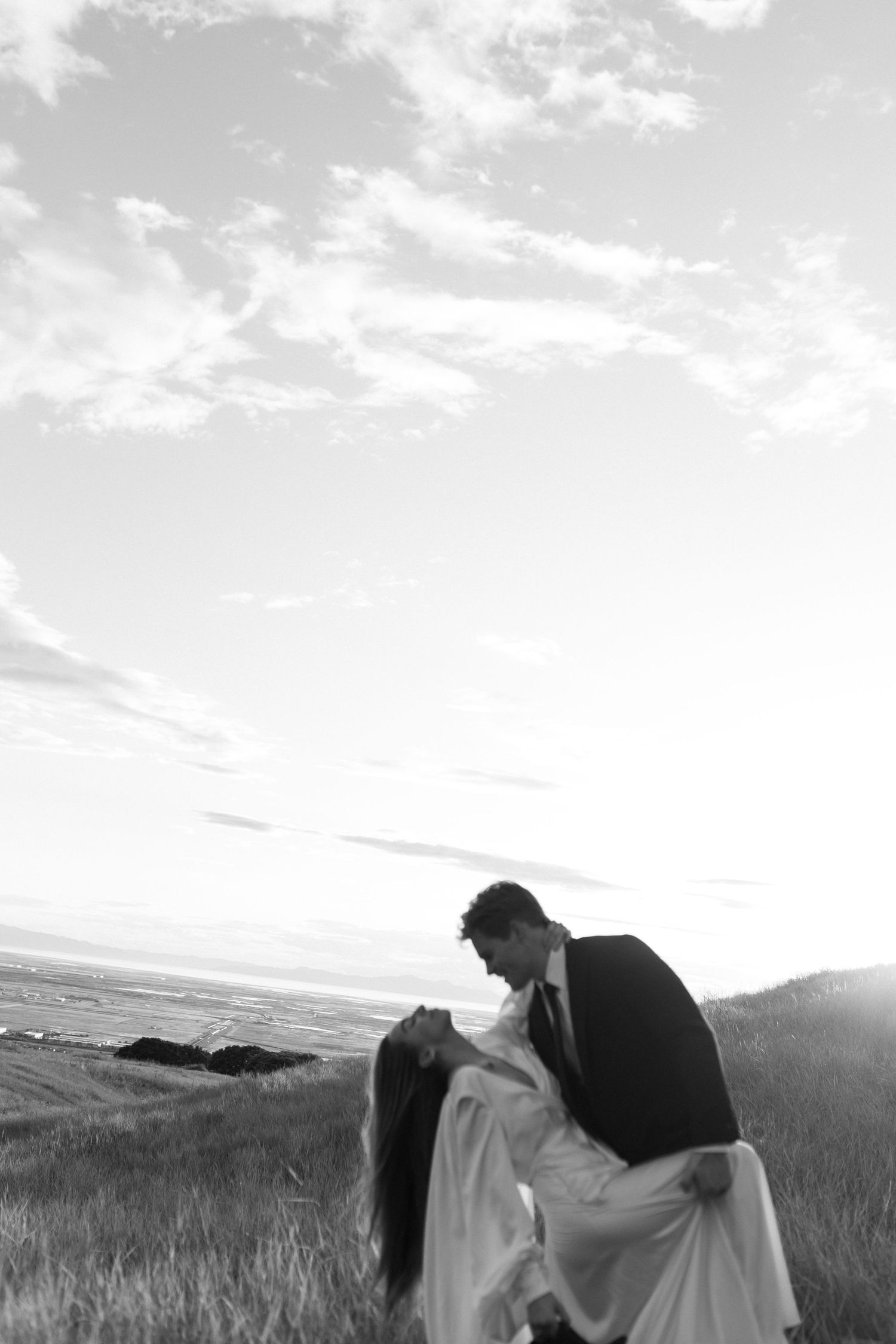 Dramatic sunset silhouette of couple in romantic pose against mountain landscape.