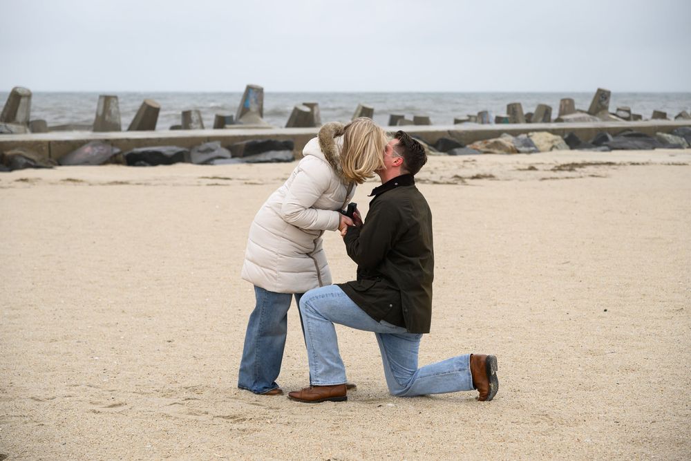 A couple shares a romantic moment during a beach proposal.