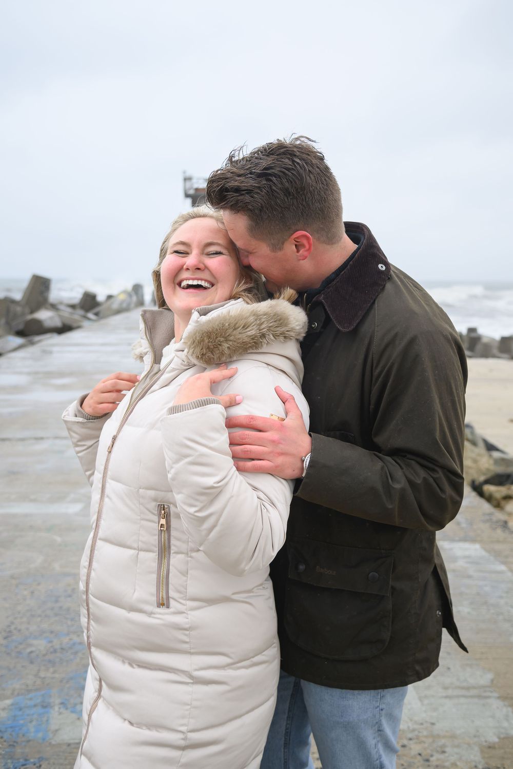 A happy couple shares a joyful moment on a rocky beach.