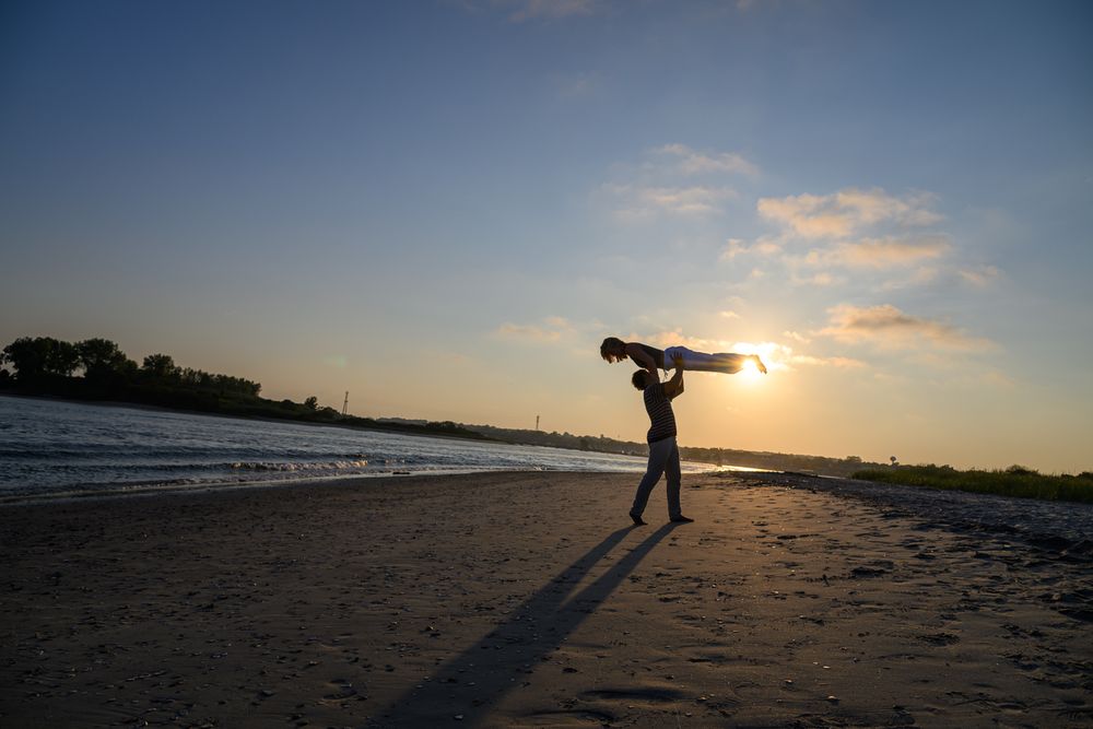 A series of silhouetted figures enjoying sunset activities on a beach with dramatic orange and purple skies.