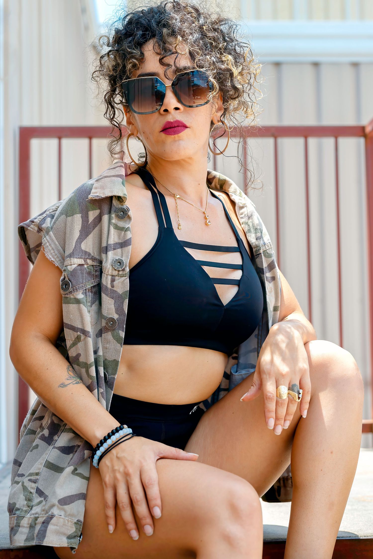 Woman in athletic wear and sunglasses posing outdoors in casual summer fashion.