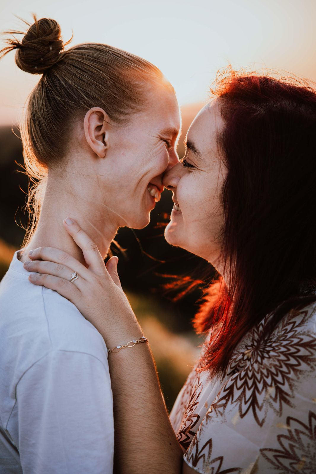 A romantic couple sharing an intimate moment at sunset with golden light illuminating their faces.