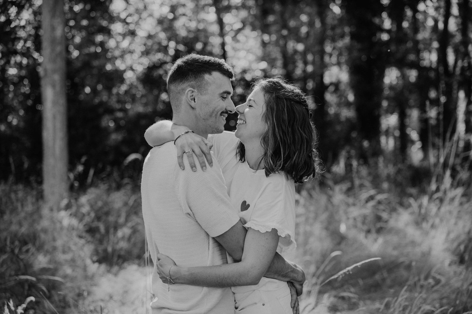 A romantic black and white photo series showing tender moments between a couple in a wooded outdoor setting.