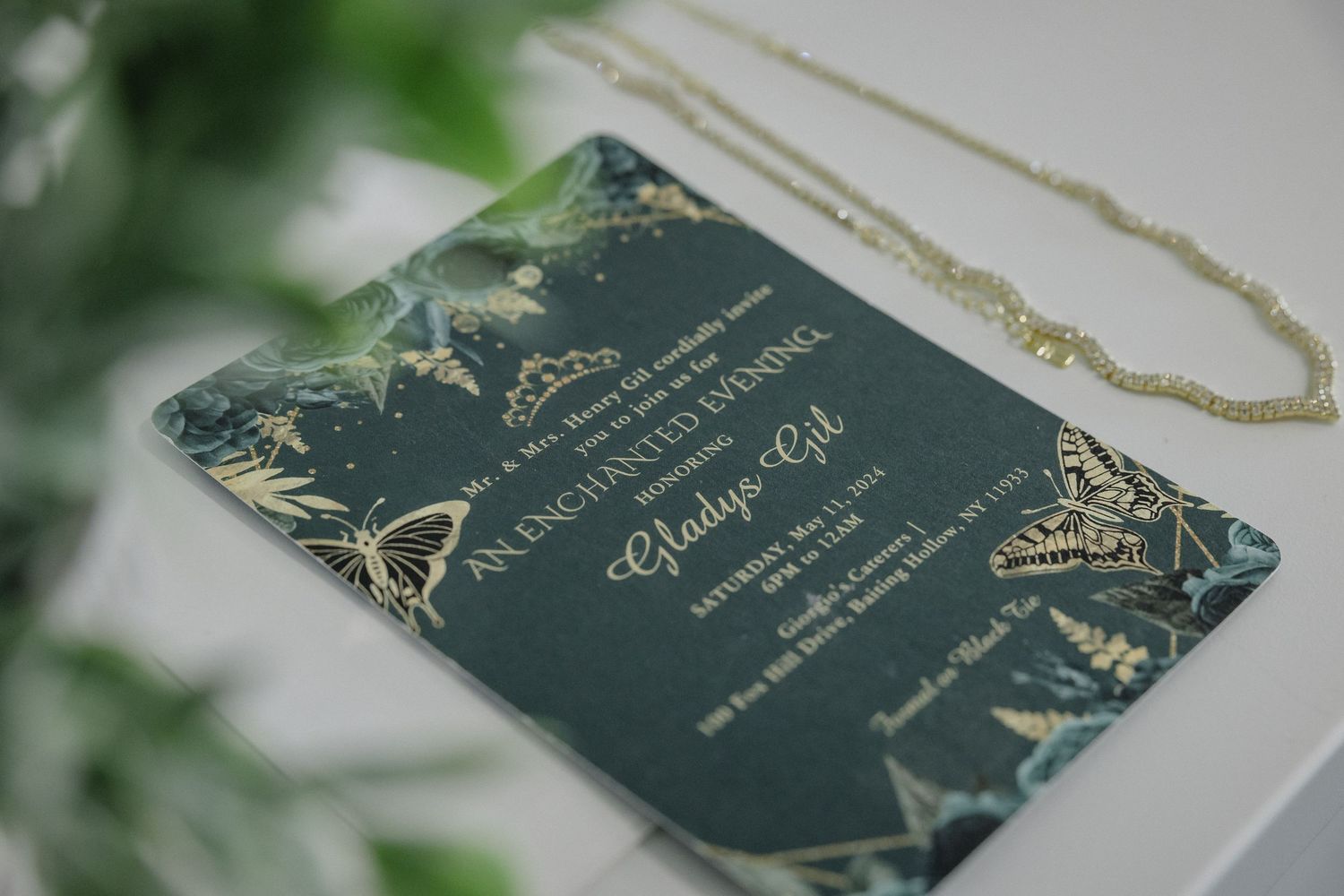 A dark teal and gold wedding invitation with elegant floral design elements.