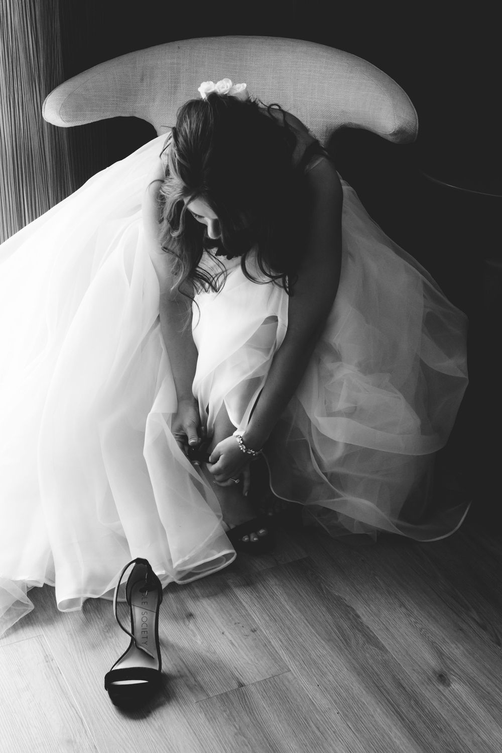 Artistic black and white photo of a bride adjusting her shoe before the wedding ceremony.