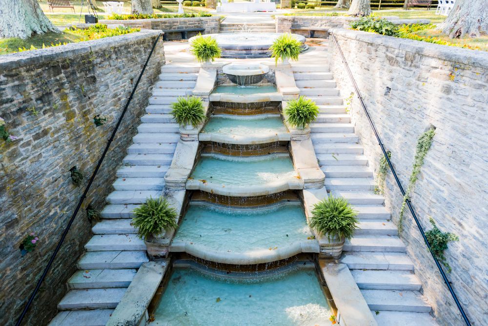 Cascading water feature with tiered steps and potted plants at an elegant wedding venue.