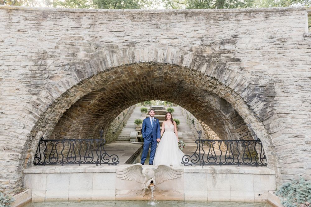 Stone archway with wedding ceremony chairs set up underneath at an outdoor venue.