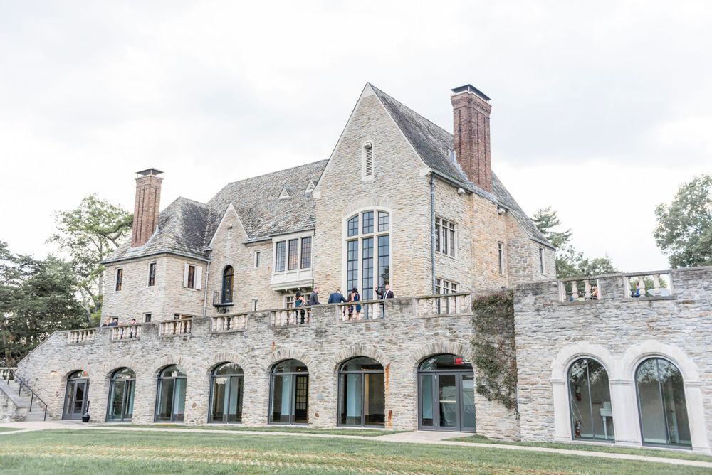 A grand stone mansion with Gothic architectural features and arched windows on a manicured lawn.