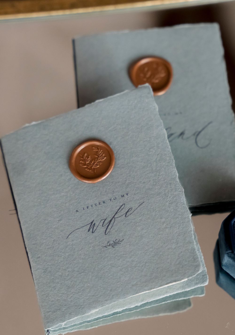 Elegant wedding stationery with copper wax seals on gray handmade paper.