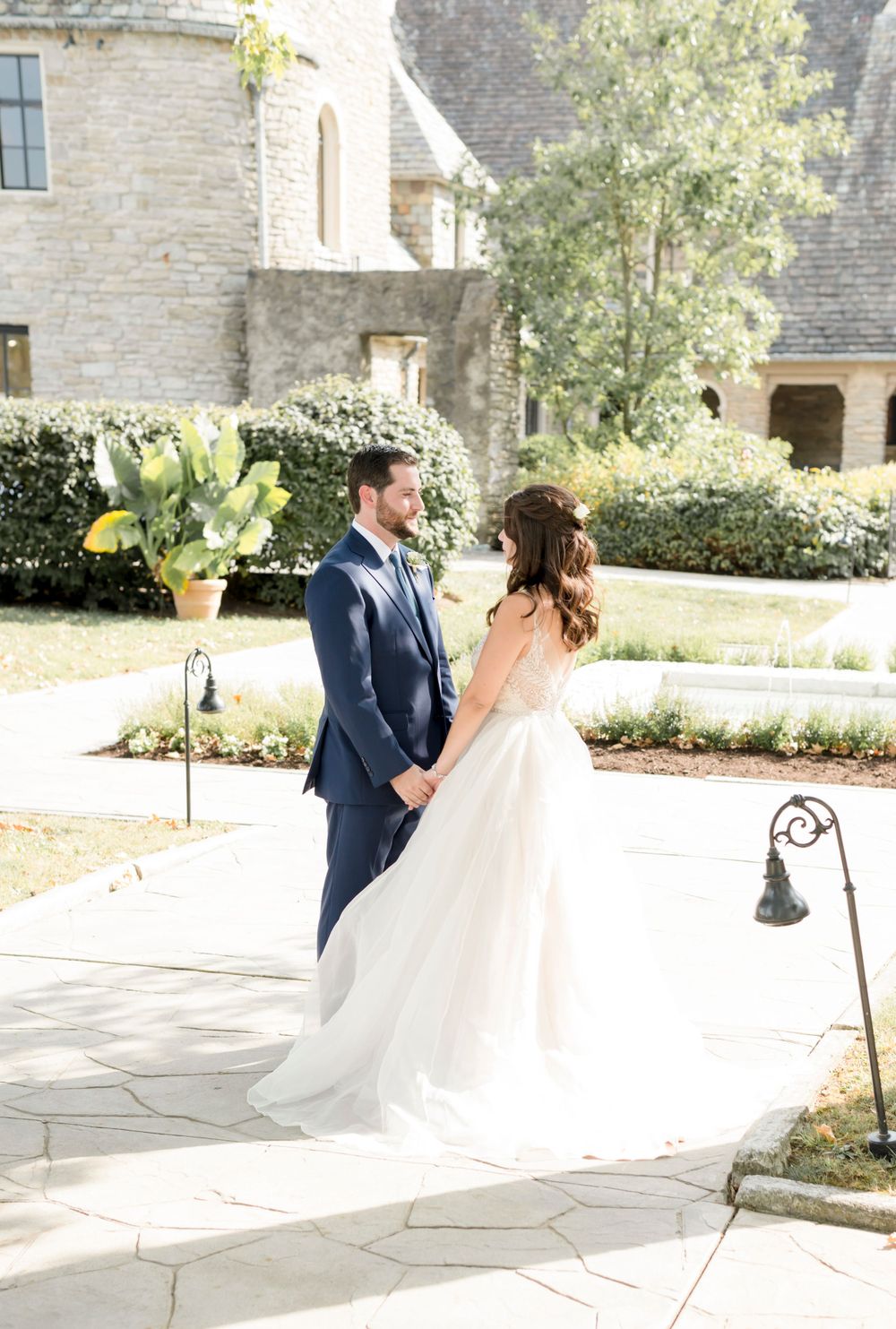 Wedding couple in elegant attire posing in front of stone castle architecture.