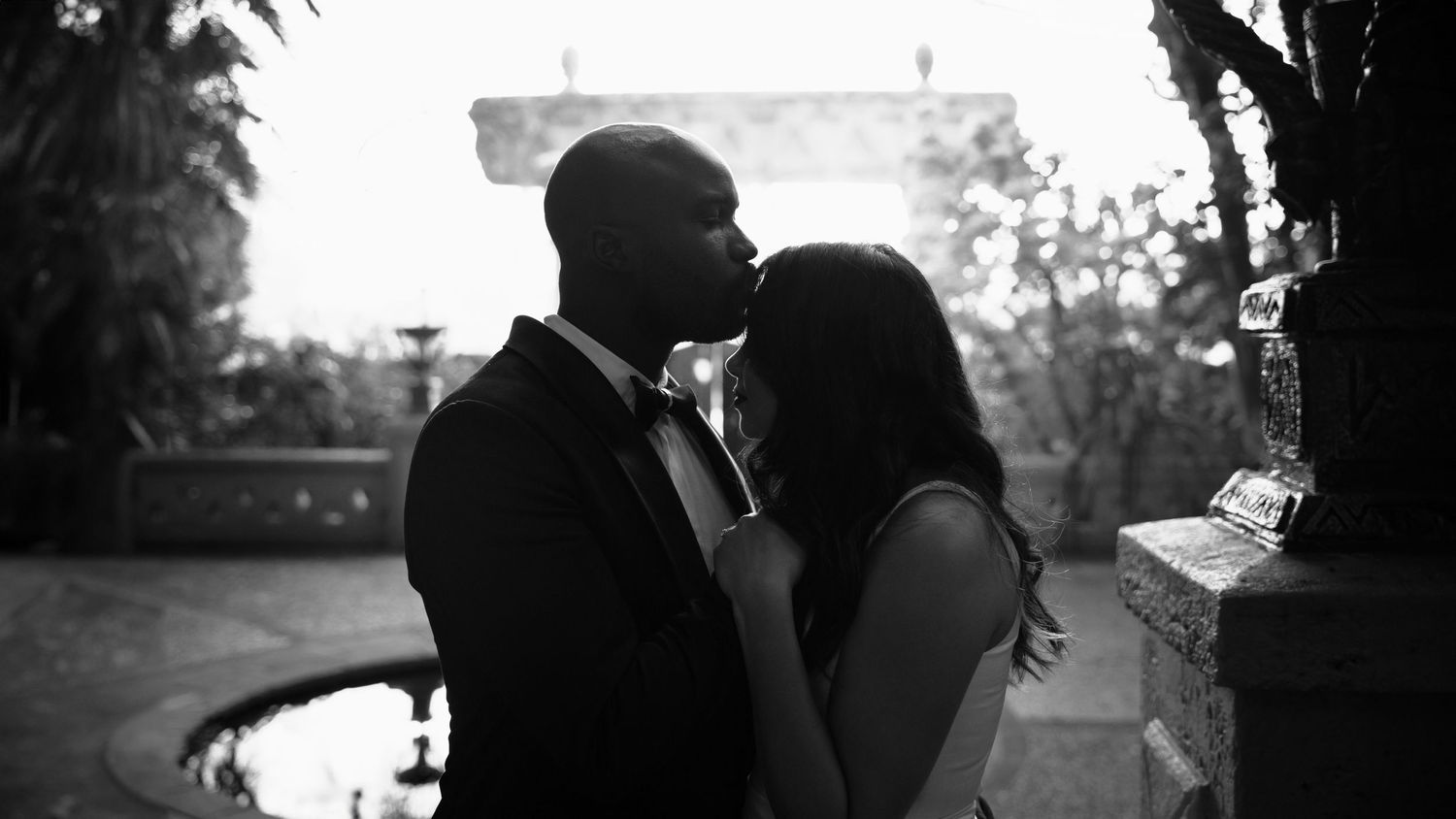 Black and white photo of couple sharing an intimate moment outdoors at dusk.