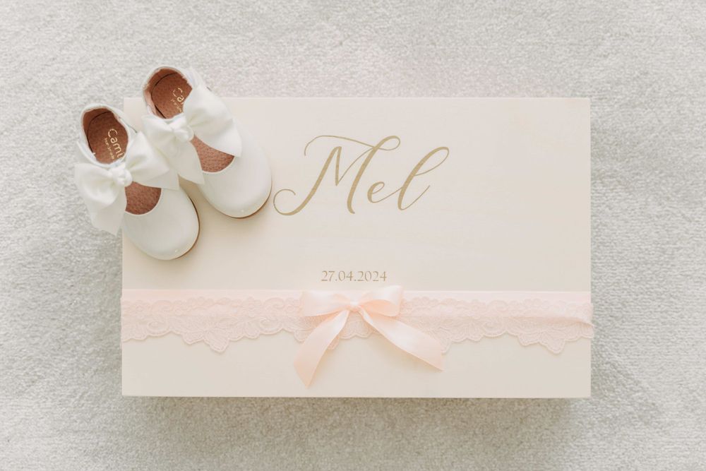 Wedding invitation with delicate peach bow and tiny white shoes.