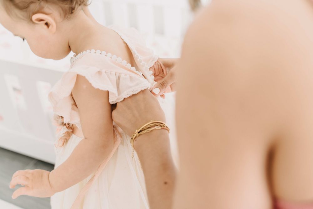 Close-up of small delicate dress with ruffled sleeves being adjusted.