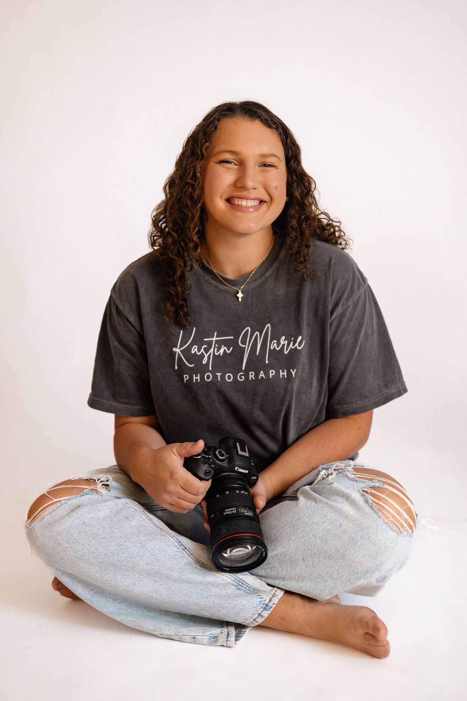 A photographer holding a professional Canon camera with a telephoto lens against a bokeh background.